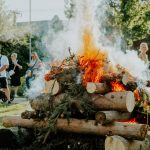 A group of people enjoying an outdoor bonfire during the day in a park setting.
