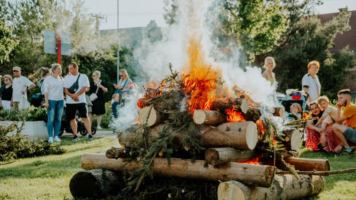 A group of people enjoying an outdoor bonfire during the day in a park setting.
